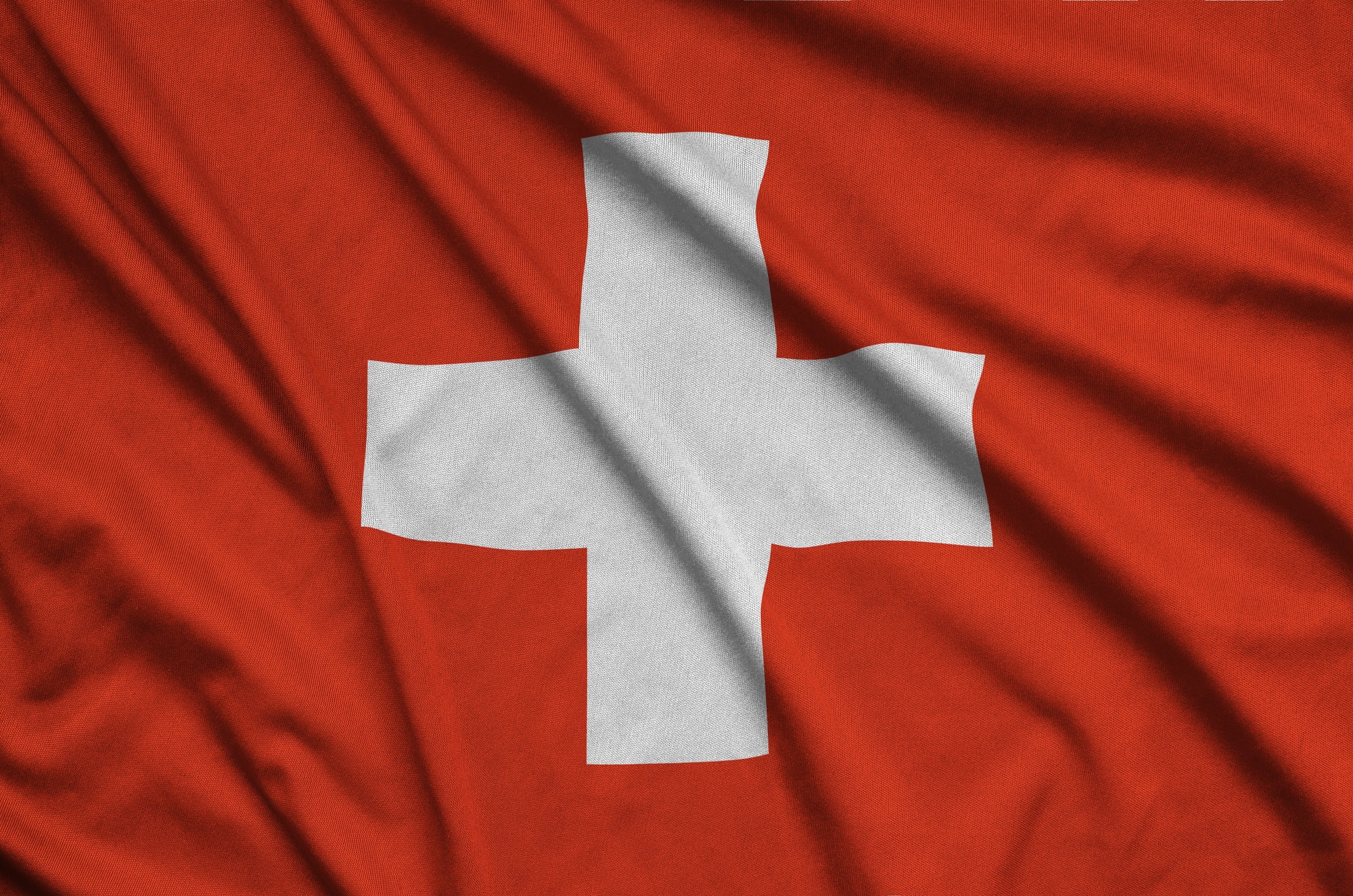 Switzerland flag is depicted on a sports cloth fabric with many folds. Sport team waving banner